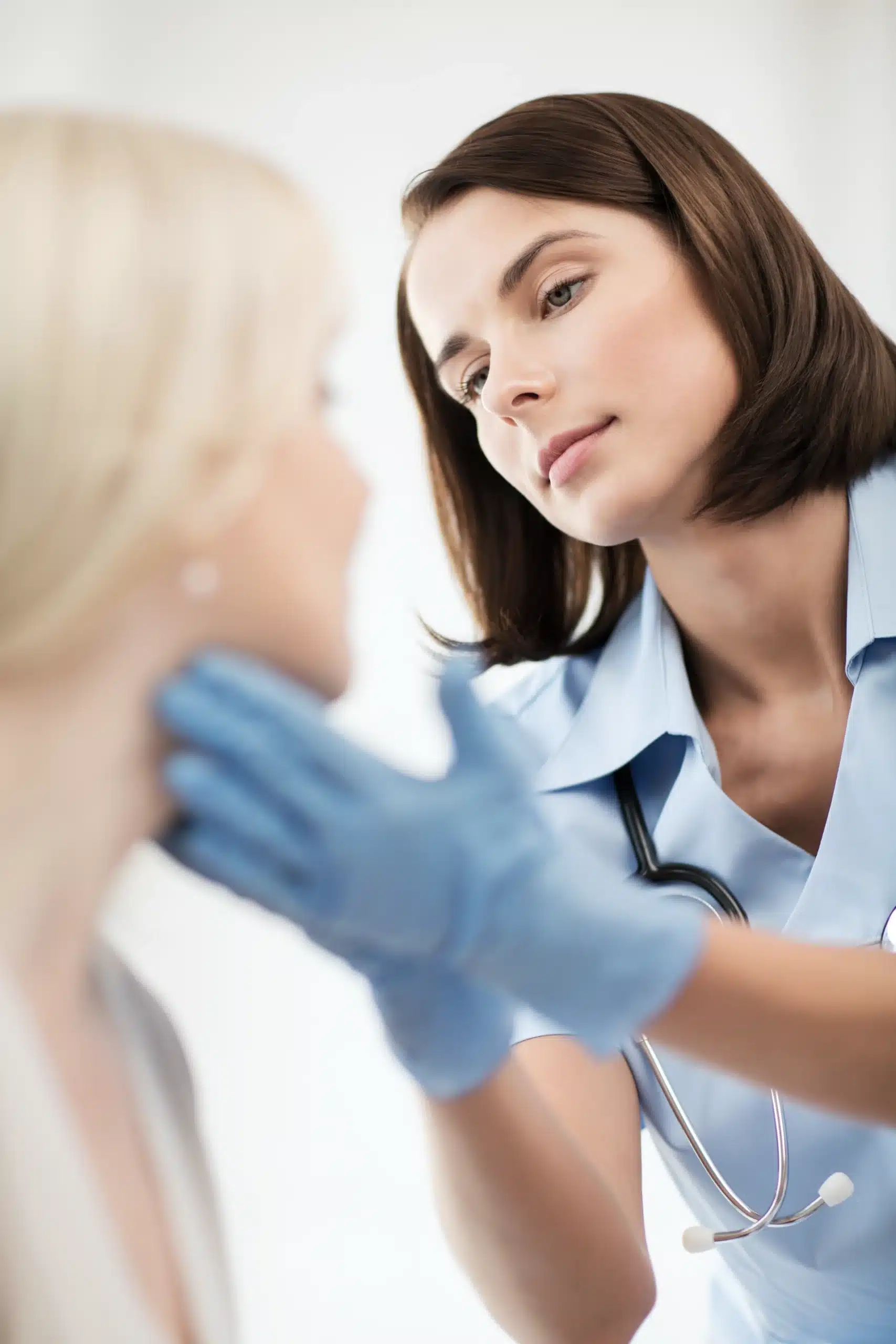 A female healthcare professional wearing blue medical gloves and a stethoscope gently examines for a surgical procedure